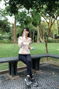 Asian woman in sportswear drinking water after workout exercise at outdoor