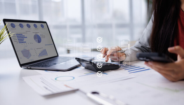 Businesswoman's hands calculating numerical results with a calculator while interacting with overlaid financial data charts and a laptop, analyzing company performance