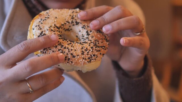 Enjoying a bagel with sesame seeds in a cozy cafe