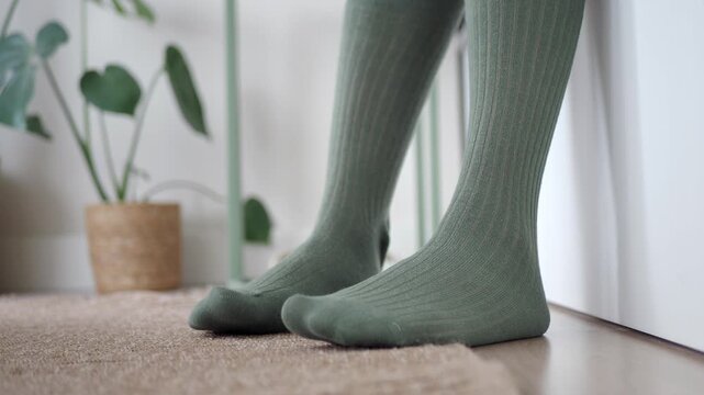 Socks on feet near potted plants in cozy indoor space