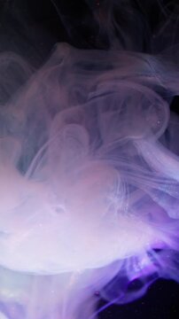 Vertical video. Glitter cloud. Paint background. Blur bright purple pink yellow color smoke splash sparkling liquid spreading on dark black abstraction.