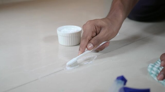 Cleaning floor tiles with brush and paste in small room