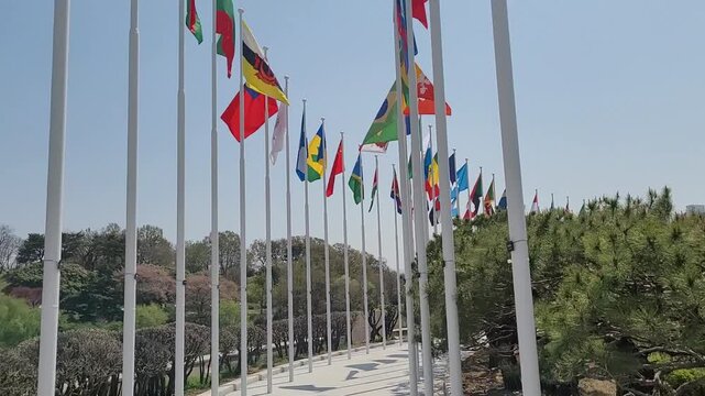 National Flags of Various Countries Fluttering in the Wind under a Clear Blue Sky
