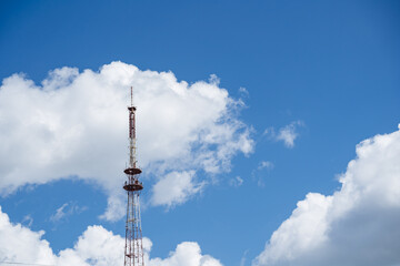Obraz premium Telecommunication tower rising into blue sky with white clouds