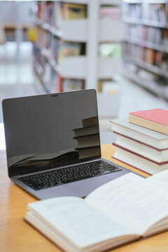 Laptop and Stack of Books in Library &ndash; Digital Education, Academic Research and Modern Learning Concept
