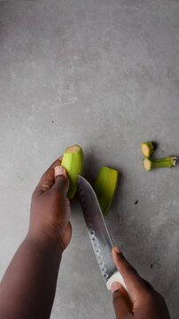 overhead view of Hands peeling unripe plantains, top view of green plantains for frying being peeled, process for making fried plantain
