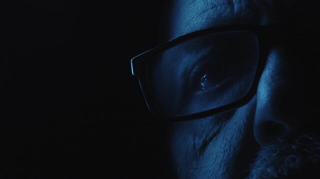 Extreme close-up of a spectacled man's eye illuminated by blue light against darkness, evoking fear, surveillance, insomnia, and psychological suspense.