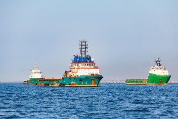 Fototapeta premium Offshore supply vessels and anchor handling tug ships anchored at open sea water near maritime port area