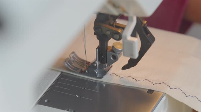 Macro of a sewing machine needle performing a specialty then a straight stitch