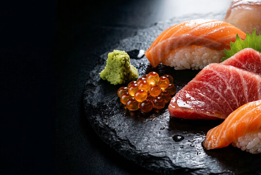 Luxury Japanese sushi and sashimi platter with salmon, tuna, ikura and wasabi on black slate