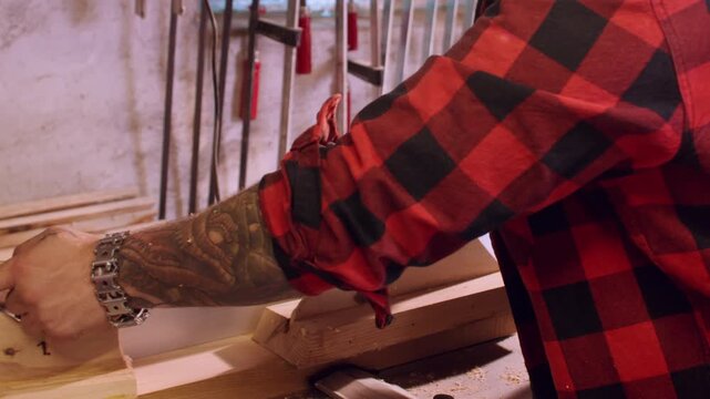 Carpentry industry. Jointer planer. Craftsman hand pushing long plank on professional electric equipment with sawdust on benchtop.