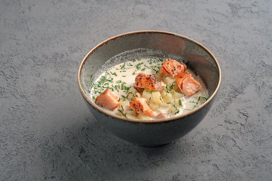 Creamy Finnish salmon soup (lohikeitto) with tender grilled salmon chunks, diced potatoes and fresh dill garnish in rustic bowl. Traditional Nordic fish chowder