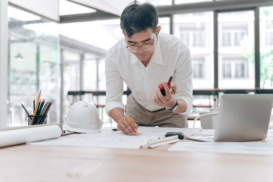 Architect Working with Blueprints and Measuring Tools in Modern Office Space