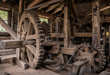 Large wooden gears and mechanical components of an old historic watermill interior showing complex craftsmanship and rustic timber construction © abdur samad