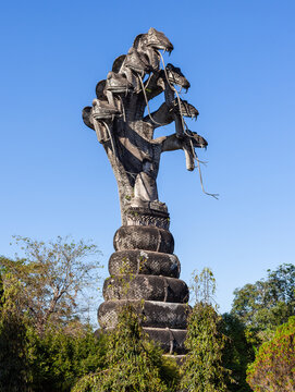 Gian Buddha with Naga statue at Sala Kaew Ku. Stone sculpture towering over lush greenery. Mystical religious monument in Nong Khai, Thailand.