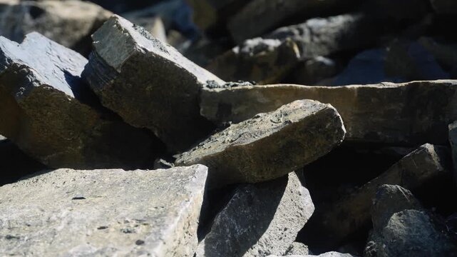 Close-up of large quarried stone blocks stacked in a rock pile. Rough-cut boulders and fractured material showcase extracted aggregate and raw construction resources from a quarry site.