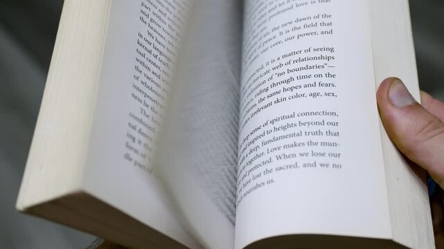 Close-Up of Hand Riffling Through Book Pages Quickly