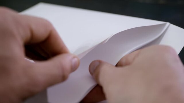 Putting a stock of paper inside an envelope. Close up of a man closing a letter and putting it in an envelope before mailing.