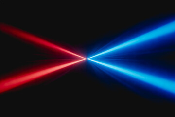 Fototapeta premium Red and blue laser beams converge towards a central point on a solid dark background, showcasing optical light effects.