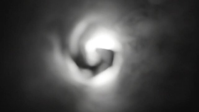 Abstract vortex swirling inside dark cloud tunnel, white light emanating from the center