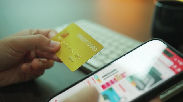 Close-up of a person holding a credit card while shopping online on a smartphone, representing digital payments and e-commerce transactions.