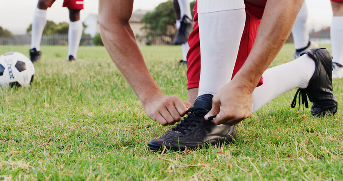 Hands, grass and soccer player tying laces for match, training or exercise outdoor on field. Sports, man and athlete with togs for preparing for football game, workout or practice for championship.