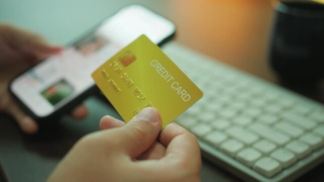 Close-up of a person holding a credit card while shopping online on a smartphone, representing digital payments and e-commerce transactions.