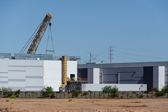 Large data center facility under construction with a lattice boom crane and structural work in progress, representing digital infrastructure expansion and technology development
