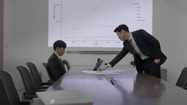 Angry Boss Scolding Employee and Pointing at Document in Office Meeting Room