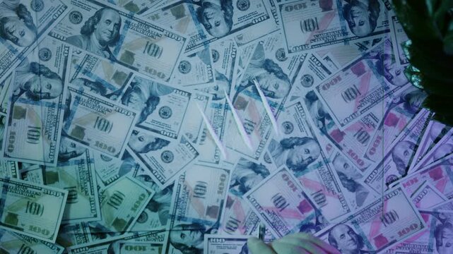 Businessman snorting cocaine lines from a table covered in hundred-dollar bills
