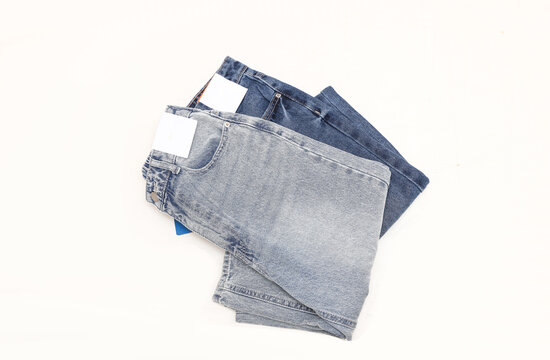 Blue straight leg baggy women's jeans with blank paper tags on white background