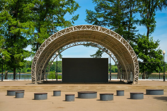 Empty outdoor stage with LED screen in riverside park, concept of open-air concerts, public events and summer entertainment.