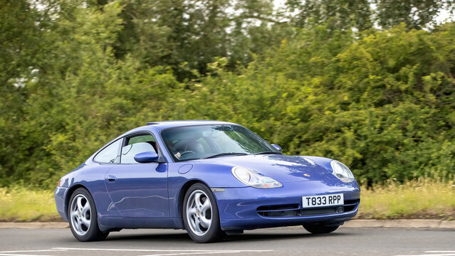 Stony Stratford,Bucks,UK - June 7th 2026:  1999 blue Porsche 911 Carrera classic car driving on a British road