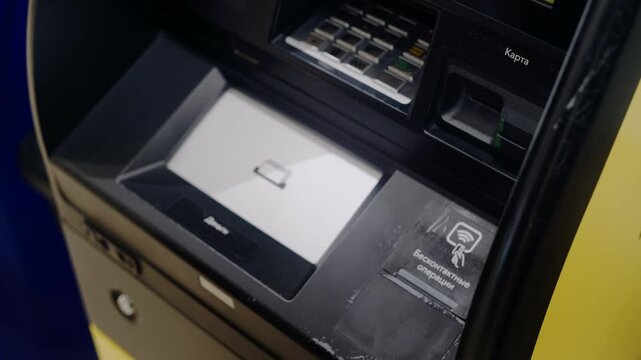 Closeup of a male hand inserting a debit card into a bank automated teller machine for a transaction