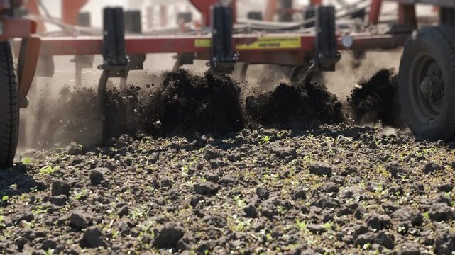 Close up of cultivator working on farmland. Agricultural machinery tilling soil and preparing field for planting during farming season.