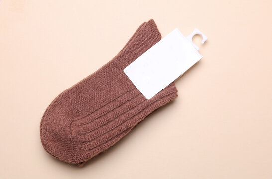 Woolen socks with a white blank tag on a beige background