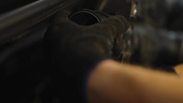 A close-up shot of a gloved hand adjusting a black plastic air intake tube inside a car engine bay