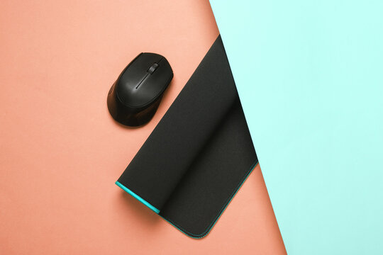 Black PC mouse with PC mouse pad on a pink blue background