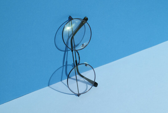 Eyeglasses on blue pastel background with shadow. Creative layout. Minimalism