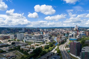 Fototapeta premium Panoramic aerial view of Leeds city centre featuring the Leeds and Liverpool Canal modern skyline residential developments commercial buildings and urban regeneration beneath dramatic summer clouds