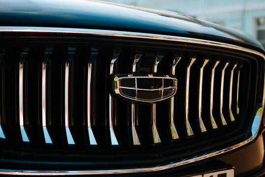 The focus is on the Geely car's front grill displaying a logo. The grill has chrome elements and vertical lines. Bright daylight makes the logo and details stand out Kazakhstan, Astana 01/06/2024