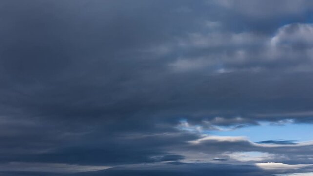 Dramatic cloudscape with dark storm clouds and glimpses of blue sky. Capturing the beauty and tension of changing weather conditions