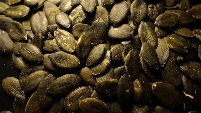 50p extreme close up shot of pumpkin seeds rotating to reveal texture