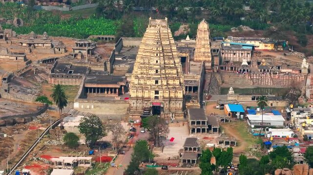 Virupaksha Temple with 100 pillared hall, Hemakuta Hill and farming land at Hampi, Vijayanagara Empire, karnataka, india. day time, push back shot, drone shot, 4k.