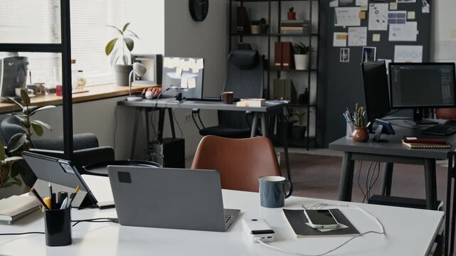 Empty modern office workspace featuring laptop, tablet, and smartphone on desk. Corporate environment suitable for business and remote work concepts