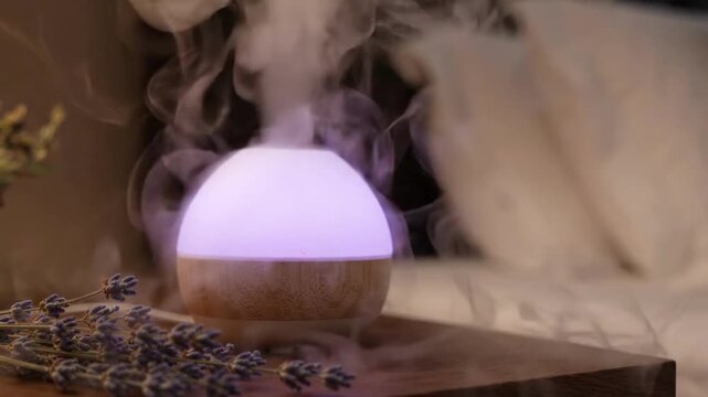 Aromatherapy diffuser emitting light and mist next to lavender sprigs
