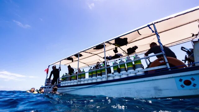 POV underwater shot breaks ocean surface at end of SCUBA Dive to show divers and boat in sunny tropical water	