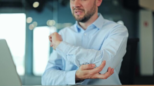 Close up of overworked businessman or IT specialist feeling arm strain, tendonitis or bone injury at laptop. Stressed manager or freelance worker suffering from severe elbow inflammation at desk
