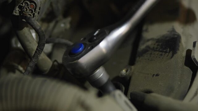 A socket ratchet wrench with blue button inside dusty engine