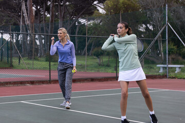 Obraz premium Female players in sportswear playing on court, right preparing backhand, left holding ball,racket